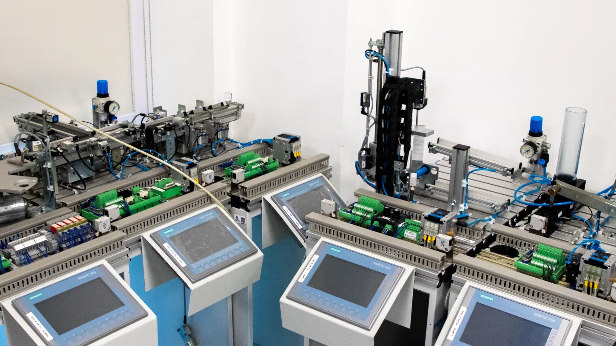 Painéis IHM e controladores em bancada de automação industrial